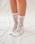 Classic sheer socks in black or white with a delicate floral pattern, solid heels, toes, and a shorter crew length.