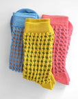 Hayes socks from Hooray Sock Co. Mid-crew length, textured ribbing, solid heel, toe, and contrasting color. In Mustard Yellow, Blue, Pink.