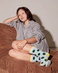 Person sitting on a brown bean bag chair wearing a checkered shirt and polka dot socks.