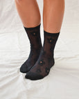 Classic sheer socks in black or white with a delicate floral pattern, solid heels, toes, and a shorter crew length.