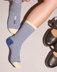 Person wearing blue striped socks and black shoes on a neutral background